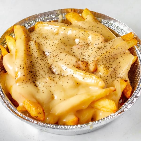 Golden french fries covered in melted cheese sauce and black pepper in a foil container.